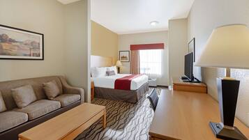 Ein Hotelzimmer mit Bett, Sofa, Schreibtisch, Fernseher und einem Bild an der Wand.