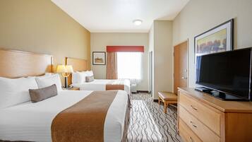 Een hotelkamer met twee bedden, een televisie, een dressoir en een raam met gordijnen.