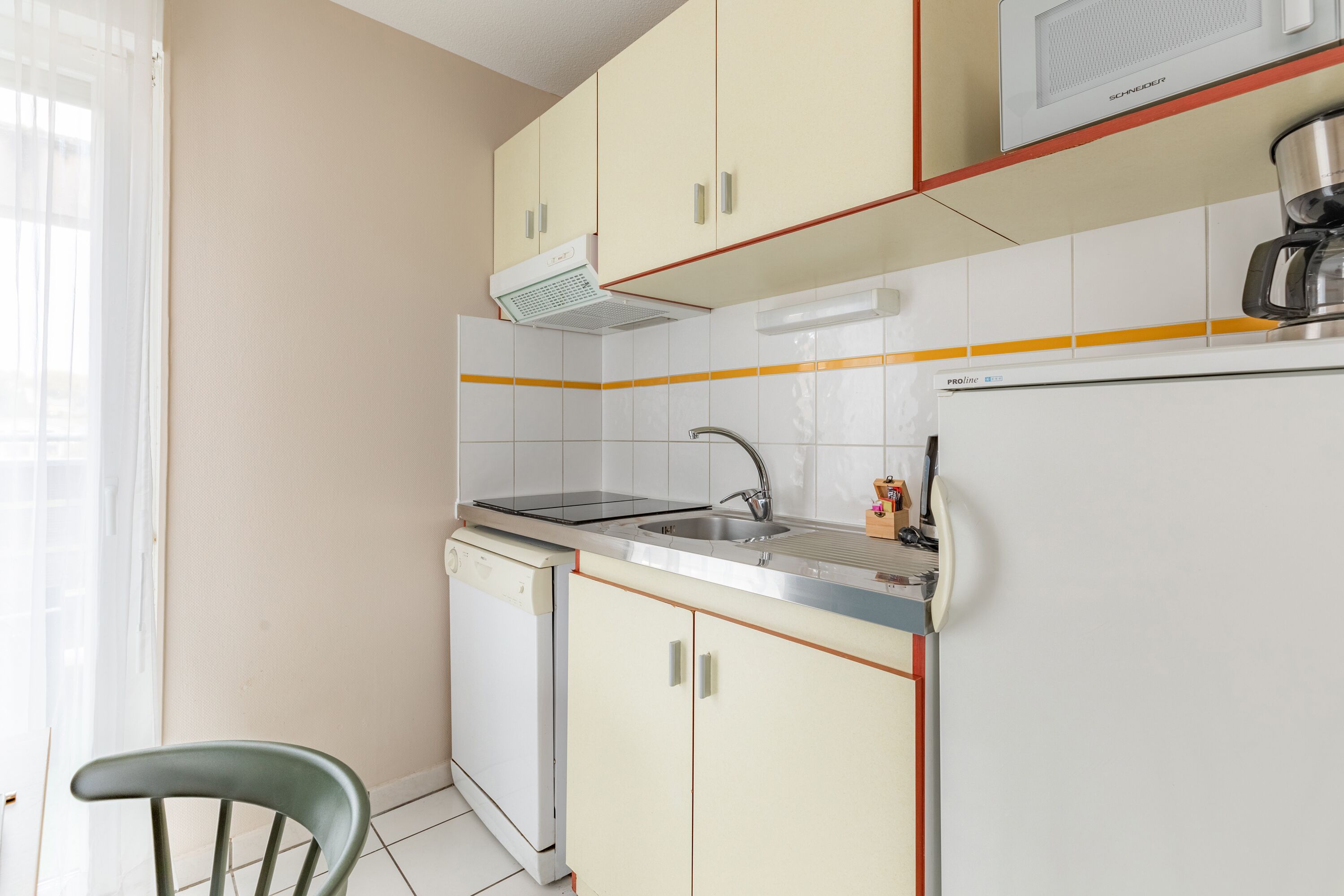 A compact kitchen with white cabinets, a built-in oven, and a coffee maker.
