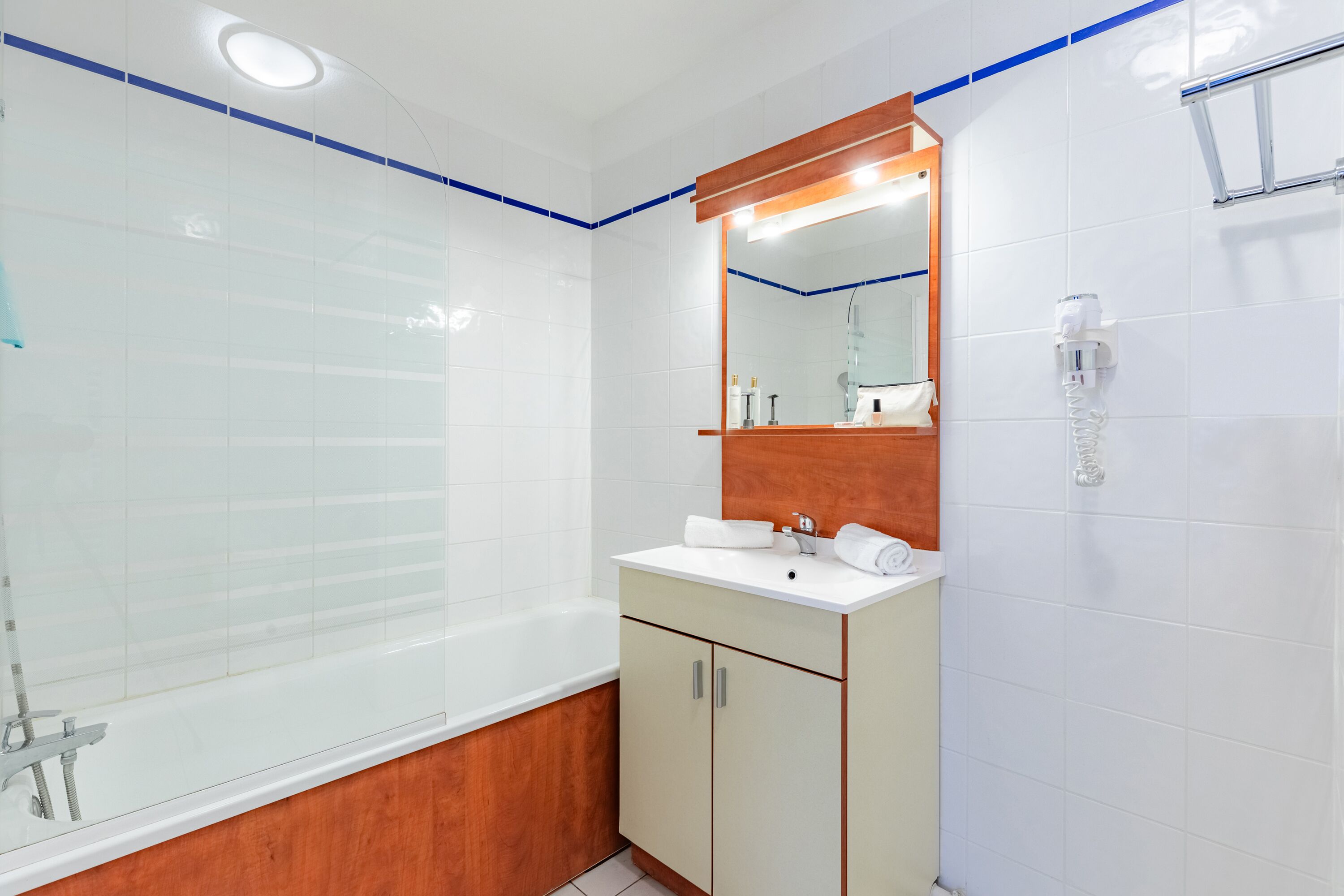 A modern bathroom with a bathtub, a vanity with a mirror, and a towel rack.