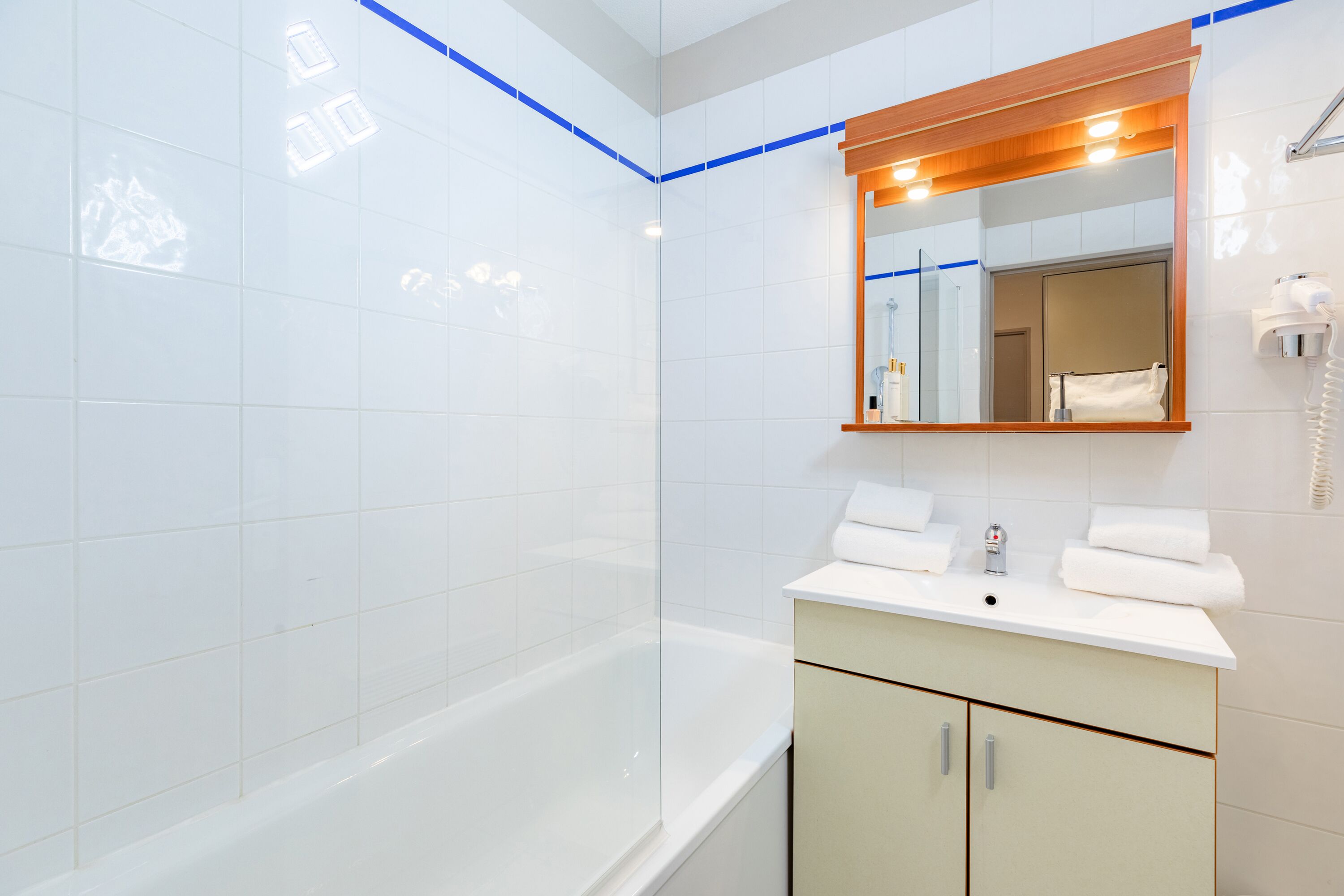A modern bathroom with a bathtub, a sink with a mirror above it, and a towel rack.