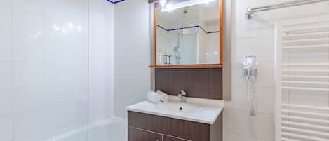 Un baño moderno con una bañera blanca, un tocador con espejo y un perchero para toallas.