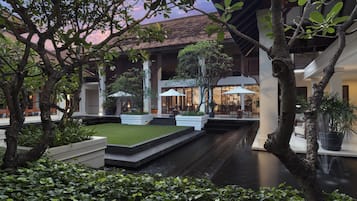 A courtyard with a water feature, potted plants, and a building with traditional architecture.