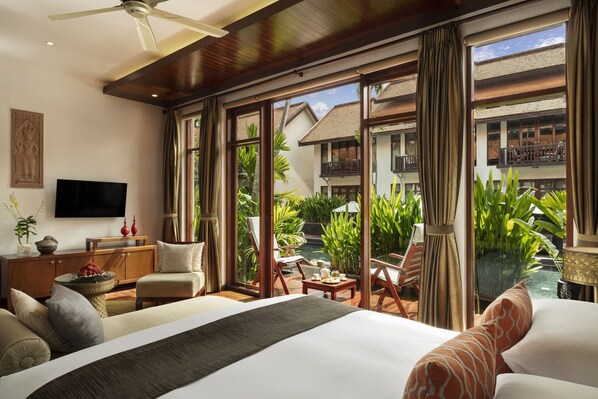 Habitación de hotel con cama, televisión, escritorio y vistas a una piscina y zonas verdes.