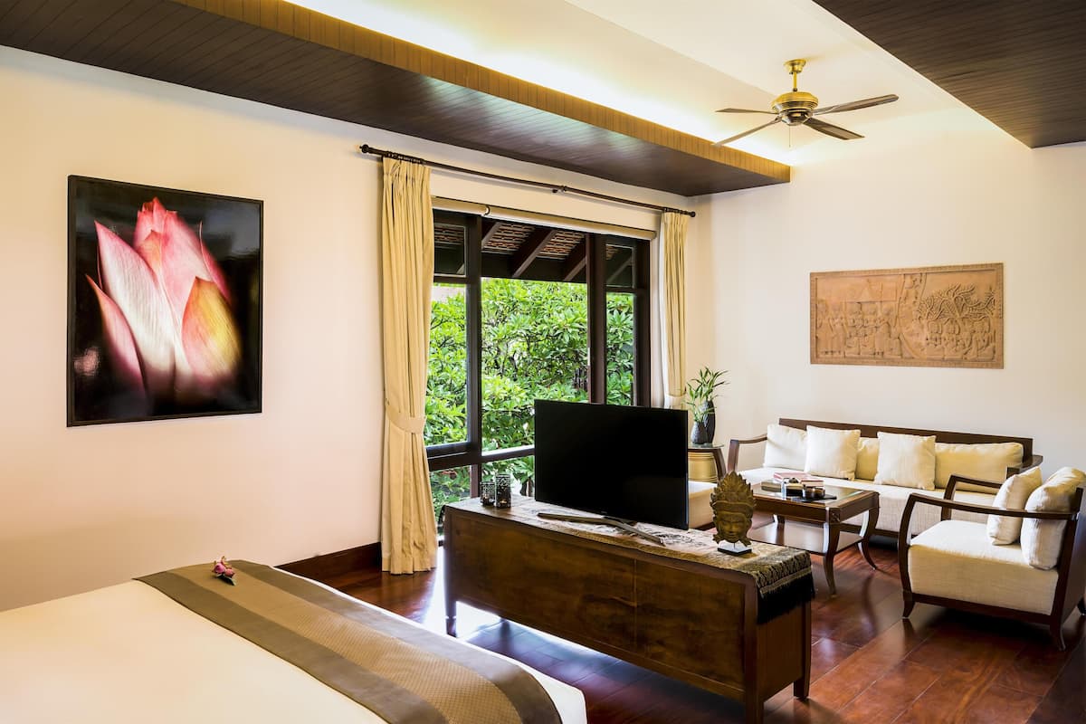 A hotel room with a bed, a desk, a chair, a television, a ceiling fan, and a window with curtains.
