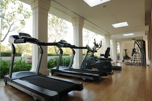 Une salle de sport équipée de tapis de course, d’un vélo d’appartement et d’un banc de musculation.