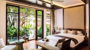 A spacious bedroom with a large bed, a ceiling fan, and a view of lush greenery outside. - Anantara Angkor Resort (Siem Reap)