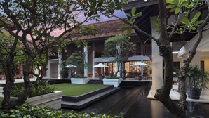 A courtyard with a water feature, seating areas, and a restaurant with umbrellas. - Anantara Angkor Resort (Siem Reap)
