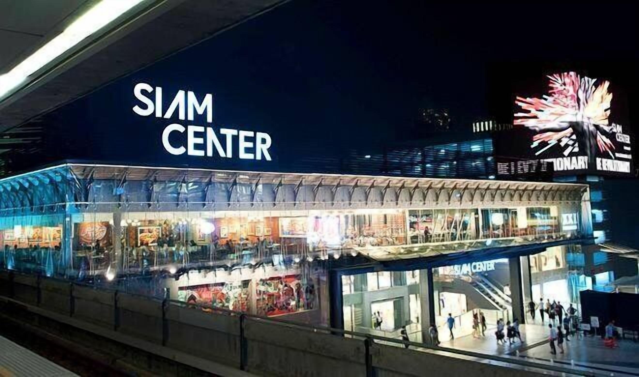The exterior of the Siam Center with a large illuminated sign, a covered walkway, and a view of the surrounding area.