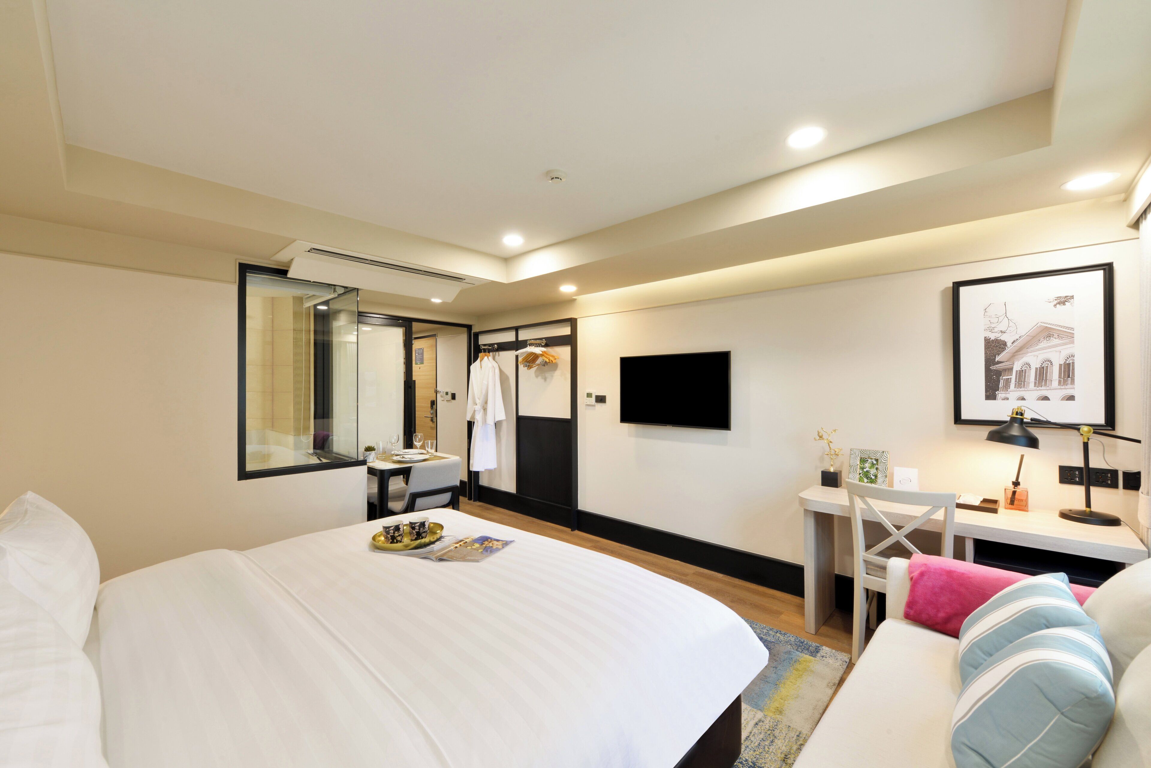 A hotel room with a large bed, a desk, a chair, a TV, and a mirror.