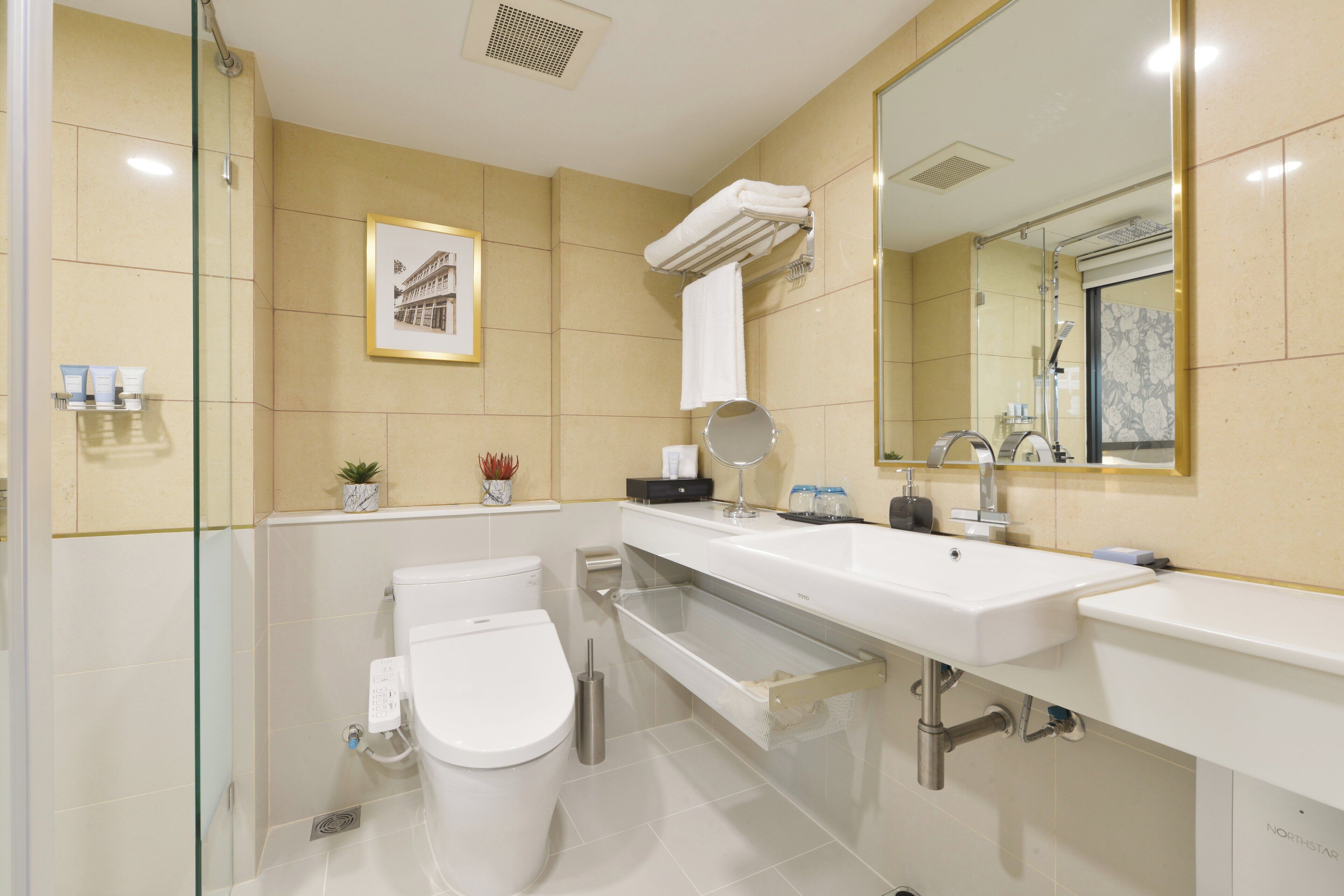 A modern bathroom with a glass shower enclosure, a white toilet, a large sink with a mirror, and a towel rack.