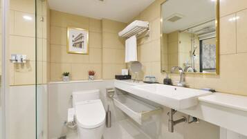 A modern bathroom with a glass shower enclosure, a white toilet, a large sink with a mirror, and a towel rack.
