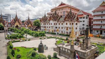 A large, traditional building with multiple ornate roofs and a central courtyard with statues and a bell.
