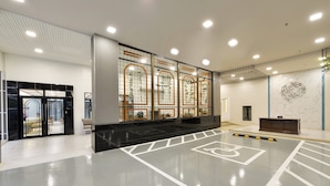 A spacious lobby with a modern design, featuring a large seating area, a reception desk, and a decorative wall with a circular pattern. - Oakwood Hotel & Residence Bangkok (Bangkok)