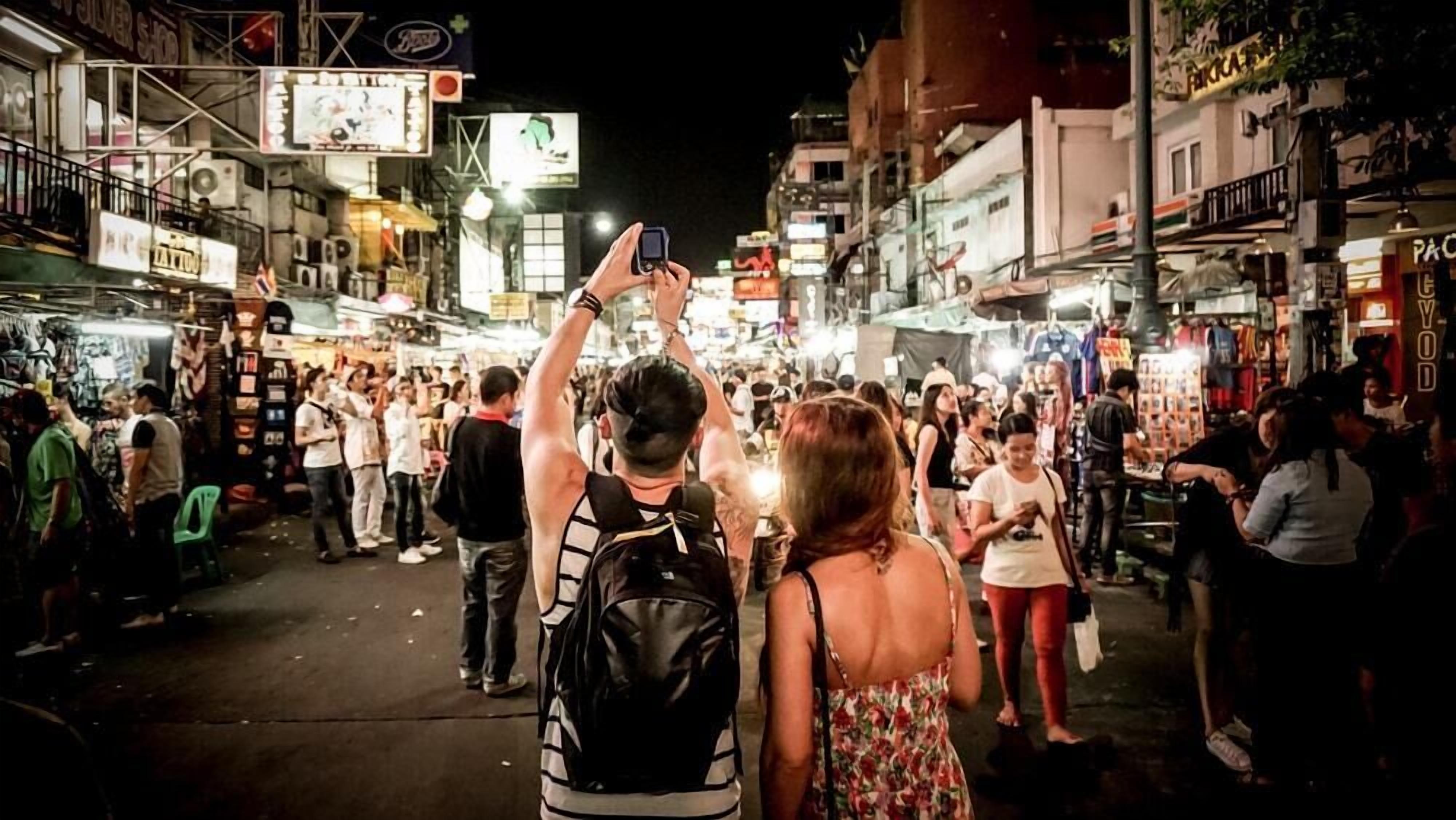 A crowded street market at night with various shops and stalls.