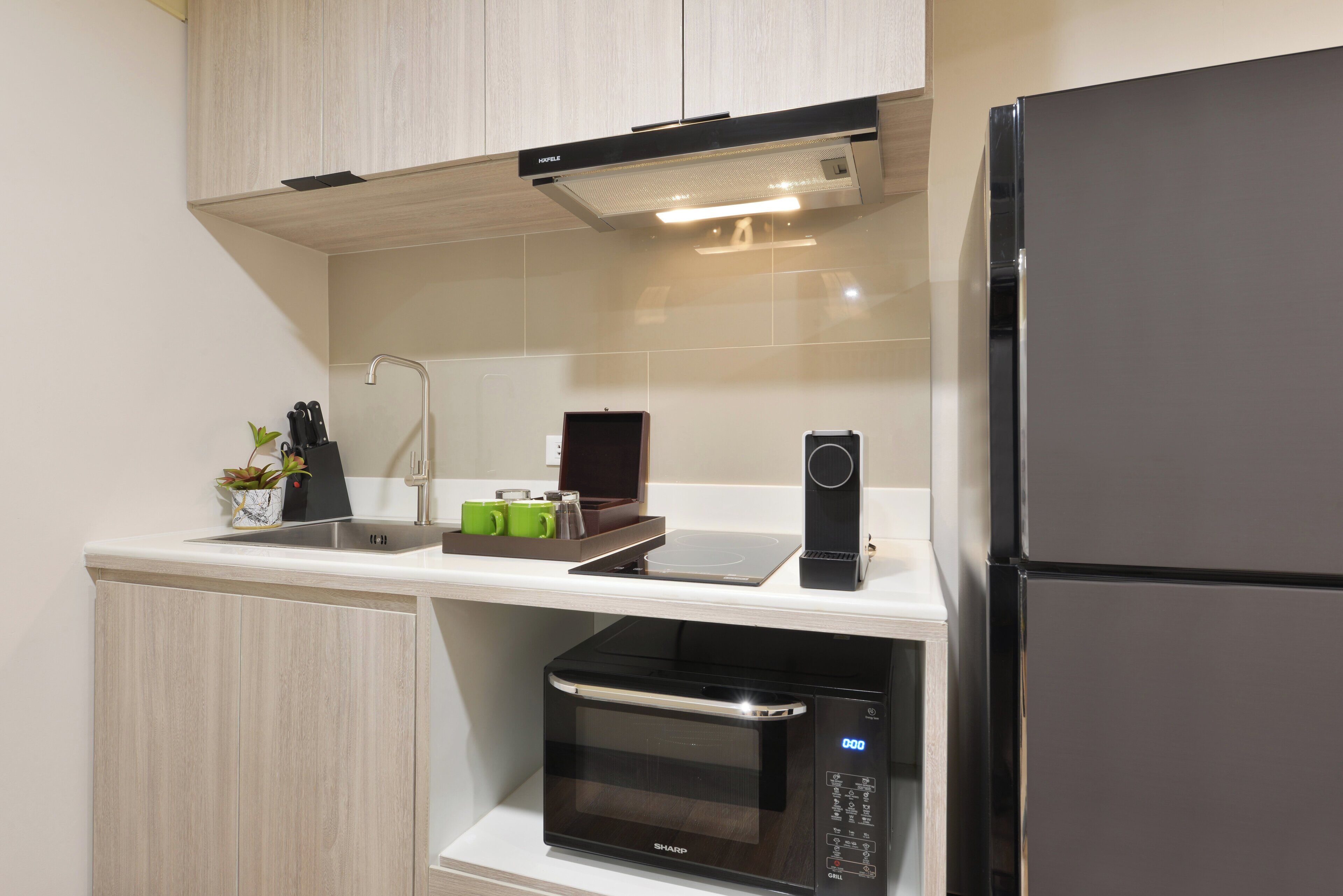 A modern kitchen with a built-in microwave, a coffee machine, and a refrigerator.