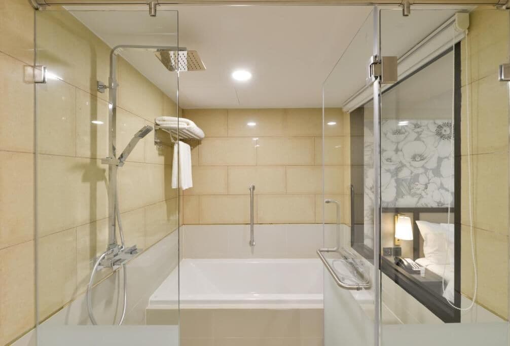 Un baño moderno con ducha de vidrio, una bañera independiente y un tocador con espejo y teléfono.