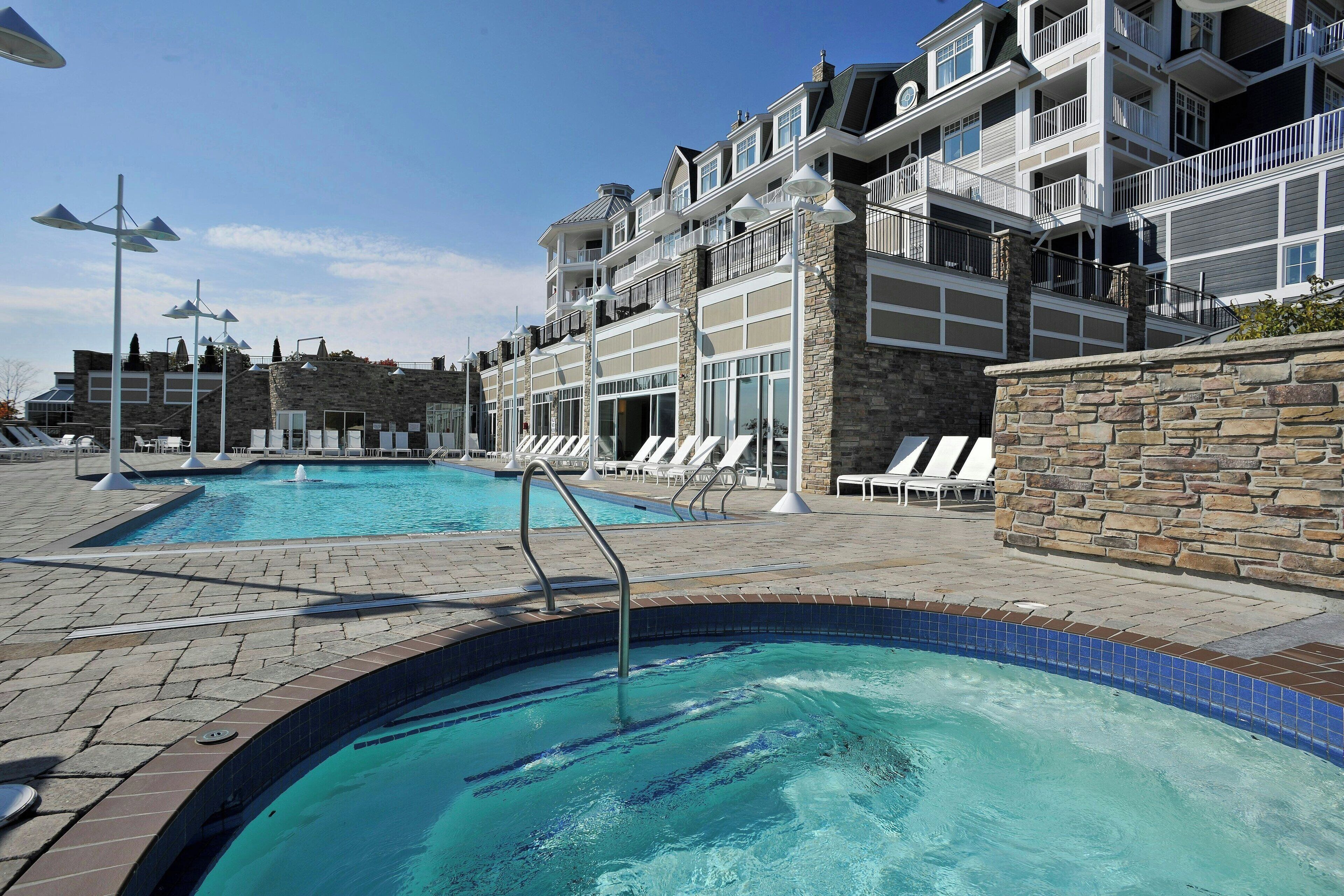 A swimming pool area with lounge chairs and a stone wall.