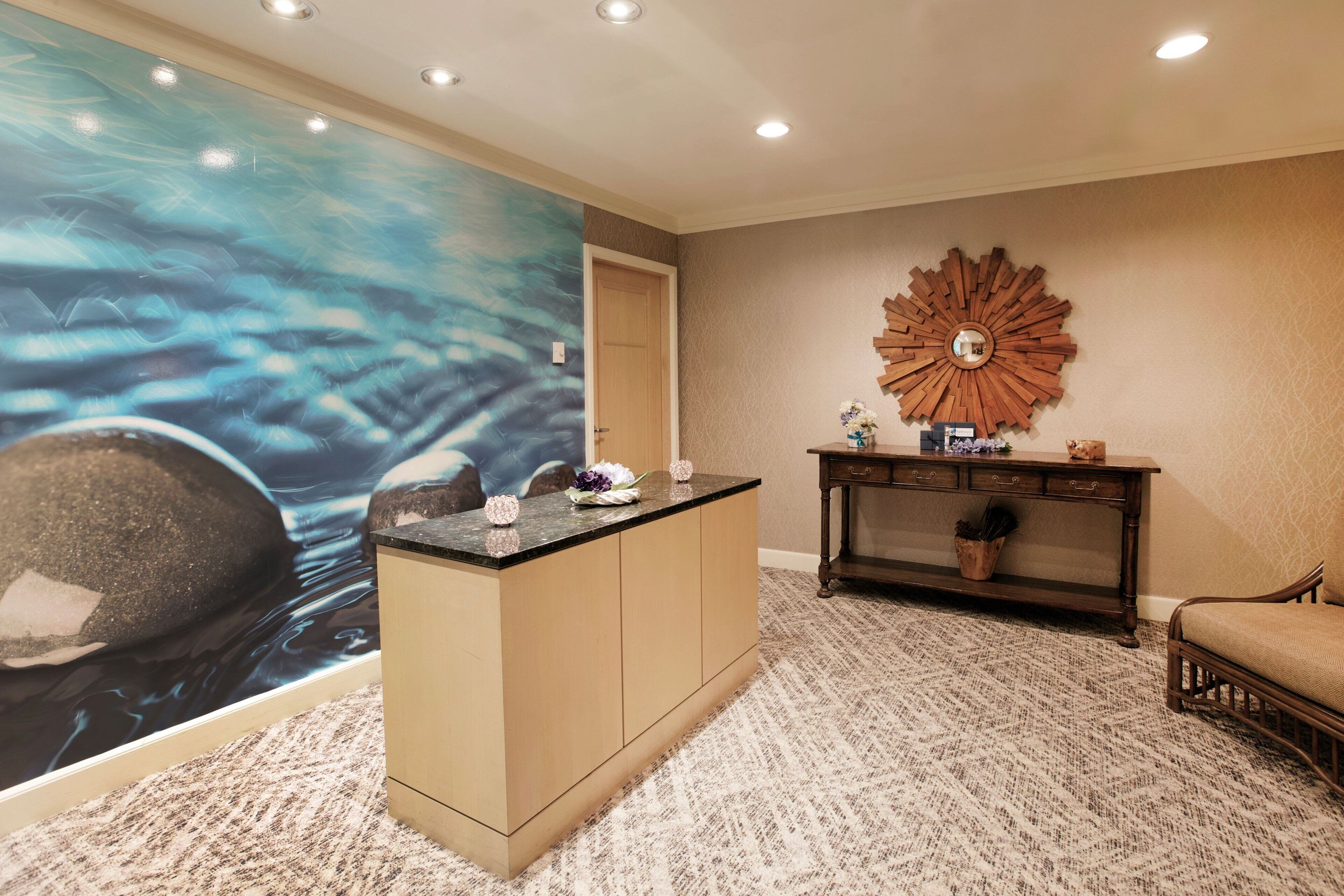 A reception area with a large abstract mural, a wooden console table, and a patterned carpet.