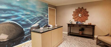 A reception area with a large abstract mural, a wooden console table, and a patterned carpet.