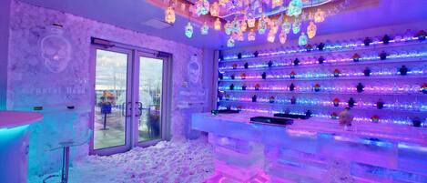 Een bar met een neonplafond en flessenkasten.