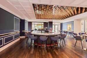 A bar area with a central bar, multiple seating options, and a decorative ceiling light fixture.