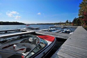 A boat docked at a pier with a clear view of the water and a forested shoreline.