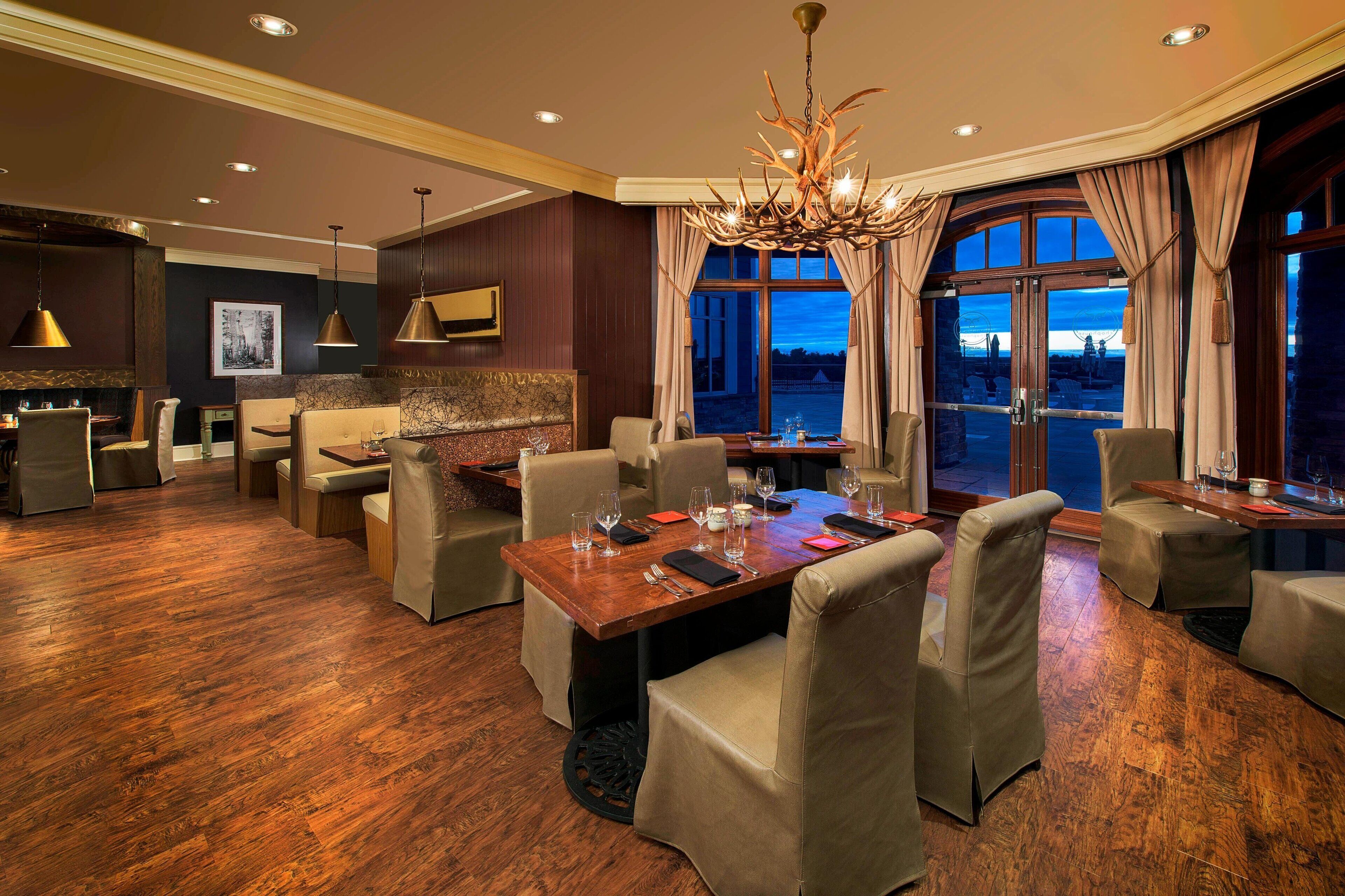 A dining area with a wooden table, beige upholstered chairs, and a chandelier.