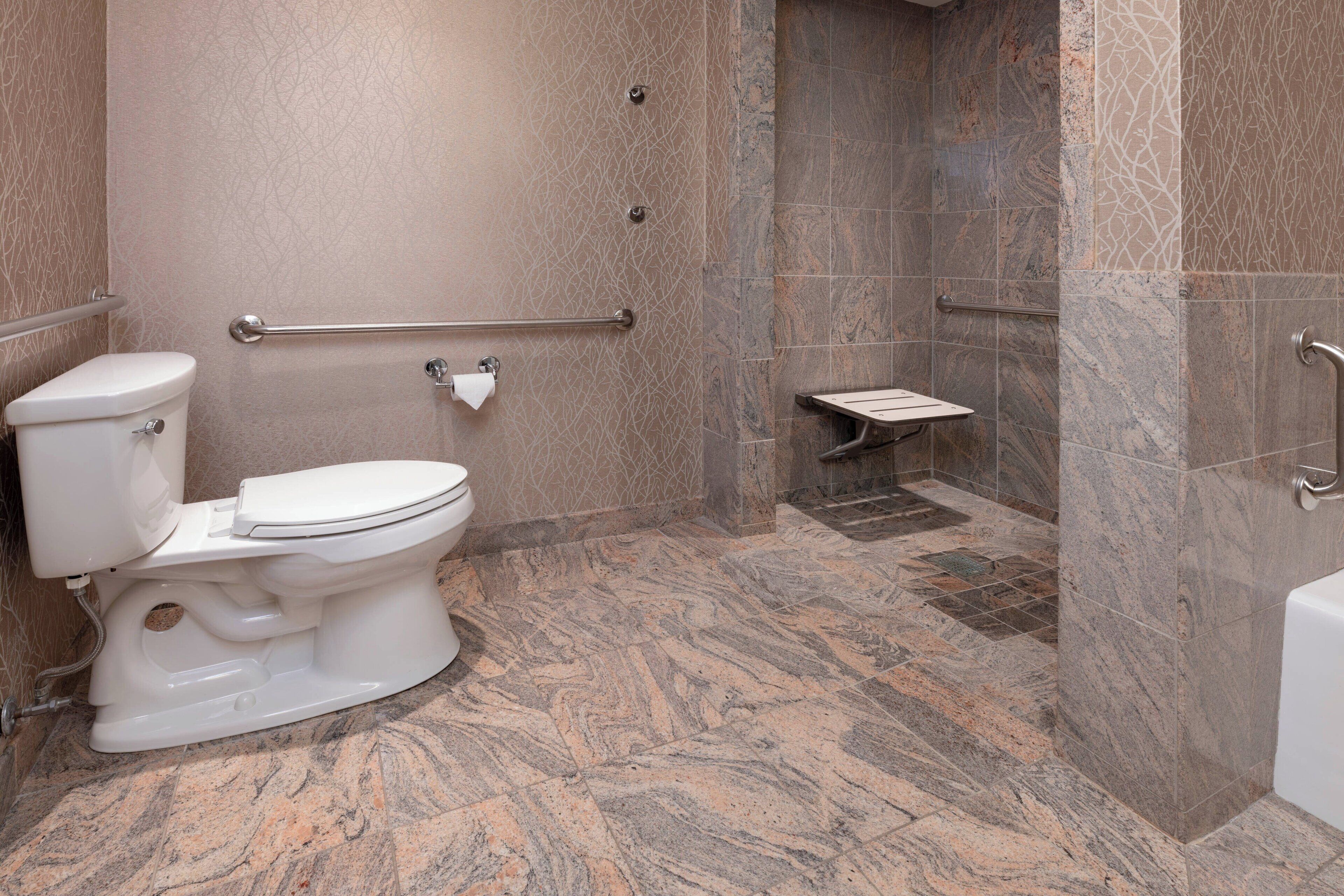 Une salle de bain comprenant des toilettes, un espace douche et un petit banc.