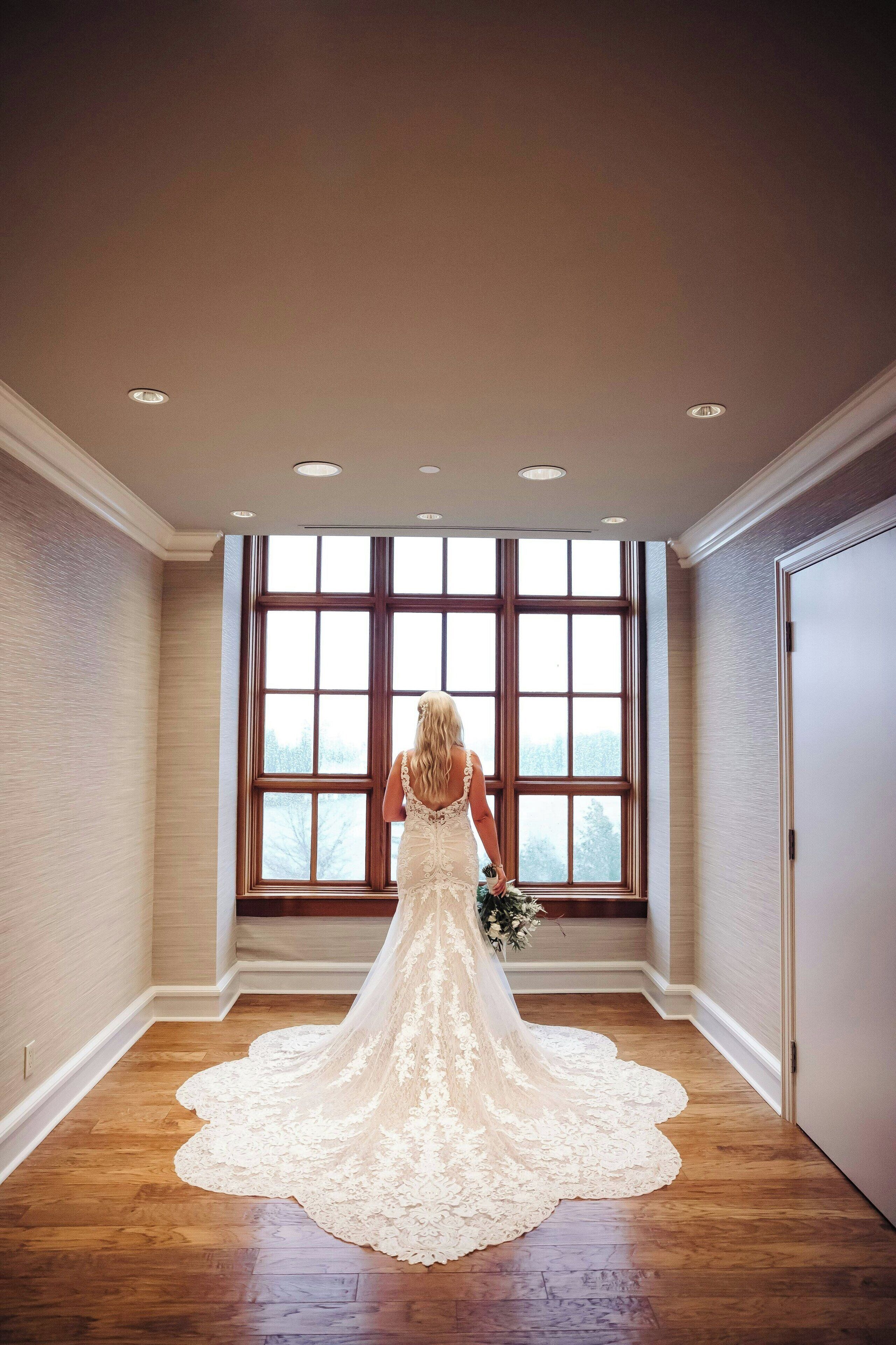 Un vestido de novia en una habitación con ventanas amplias y suelo de madera.