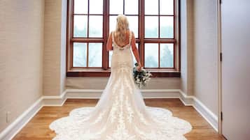 Un vestido de novia en una habitación con ventanas amplias y suelo de madera.