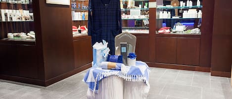 Eine Lobby eines Boutique-Hotels mit einem zentralen Ausstelltisch, einem aufgehängten Kleidungsstück und Regalen mit Toilettenartikeln.