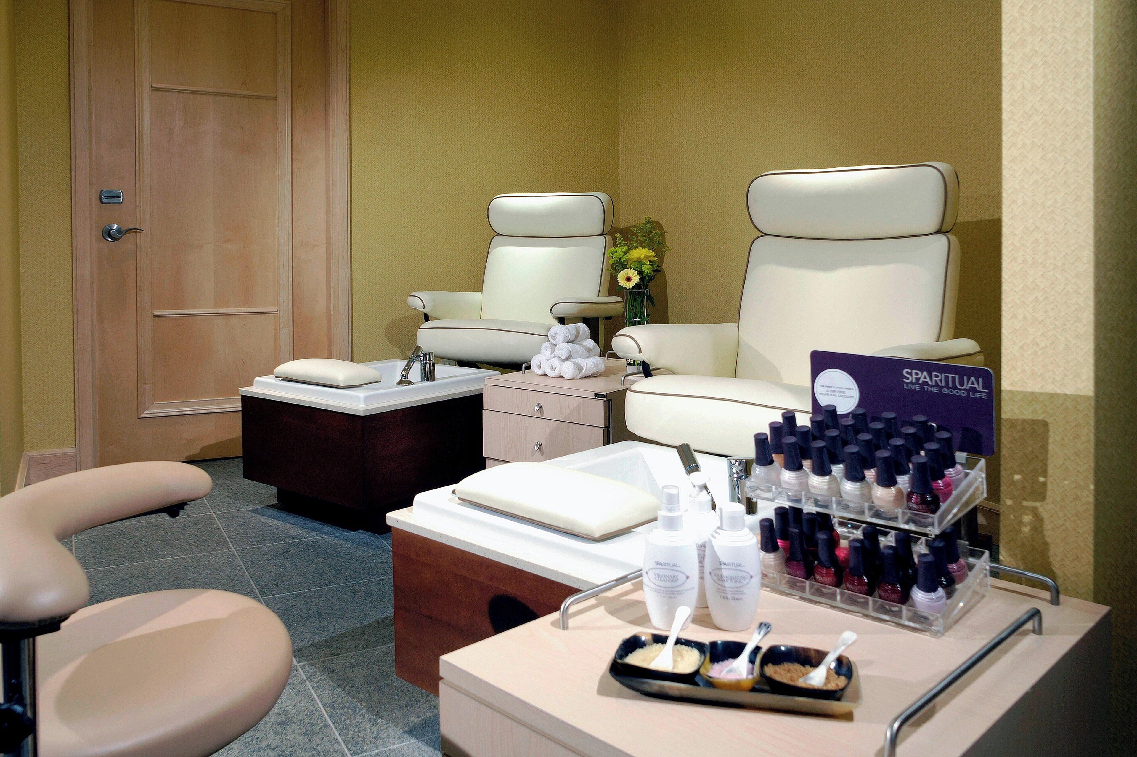 Un cuarto de spa con dos sillas de masaje, un tocador con lavamanos y una exhibición de productos de spa.