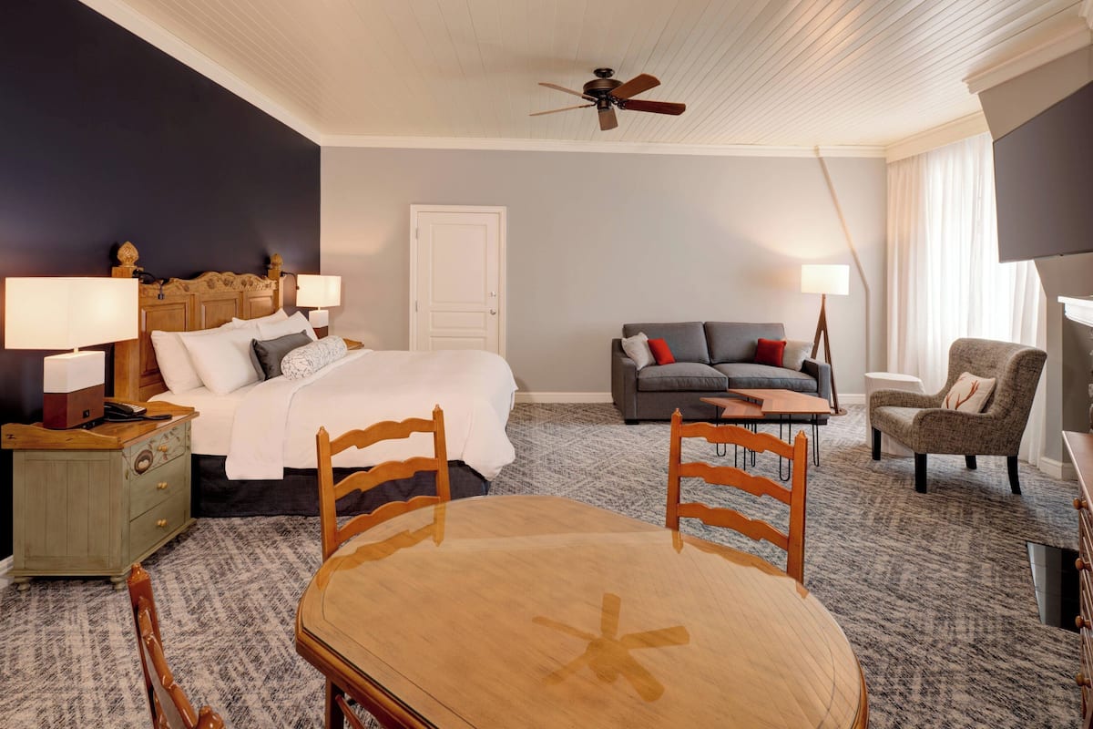 Una habitación de hotel con una cama, un sofá, una mesa de comedor y un televisor.