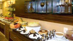 A buffet with various food items, including fruits, cakes, and a coffee station.