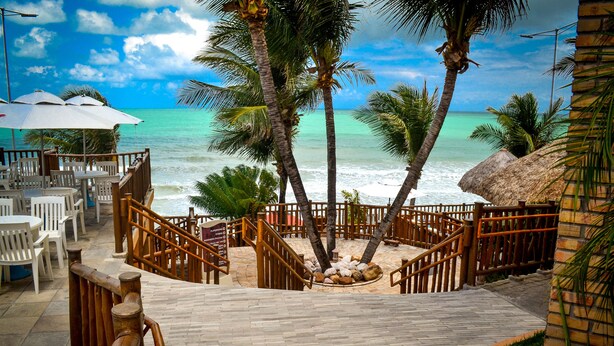 A wooden deck with outdoor seating overlooking a beach.