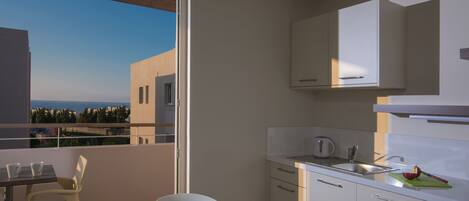 A modern kitchen with a view of the sea, a dining area with a table and chairs, and a balcony with a glass door.
