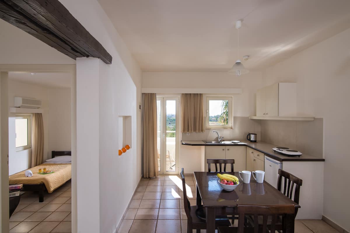 A compact kitchen with a dining table, chairs, and a window.