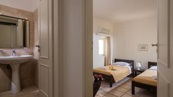Una habitación de hotel con baño, una cama, una mesita de noche y una ventana.