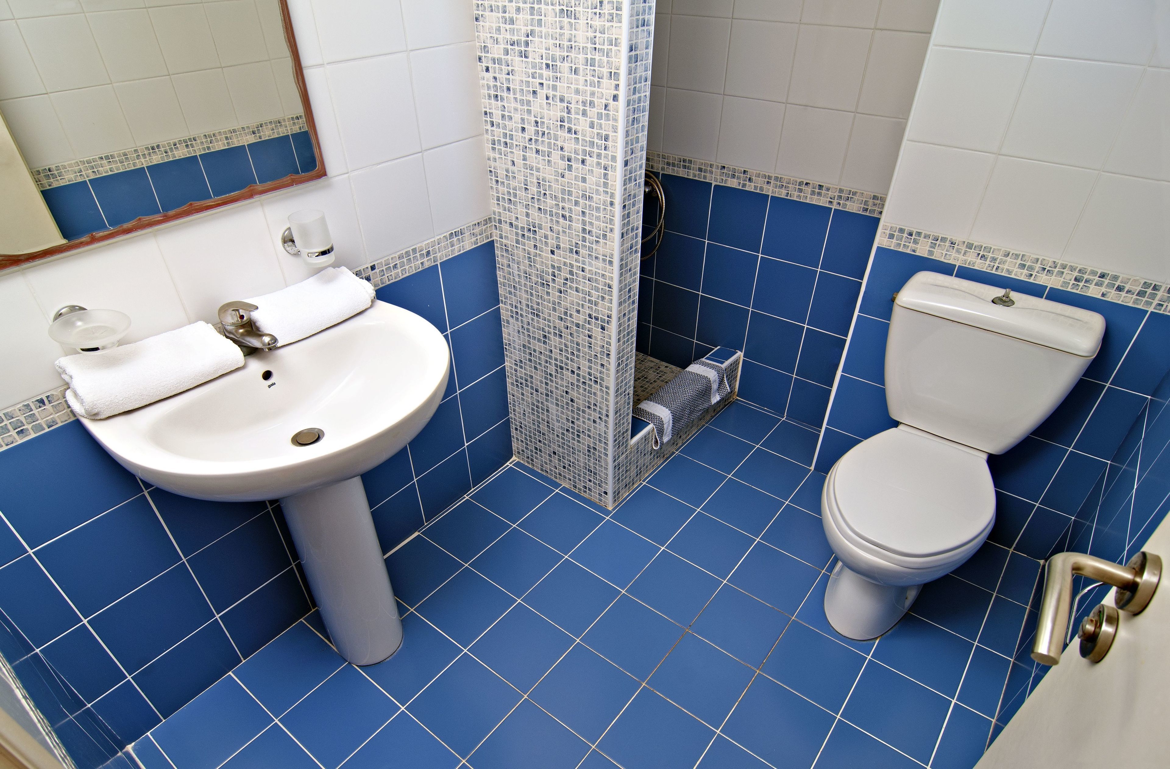 Un baño con lavamanos blanco, inodoro y paredes con azulejos azules.