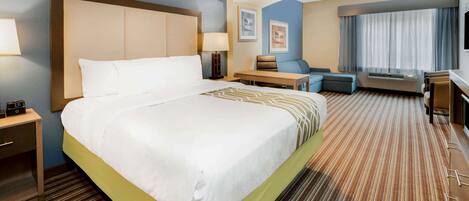 A hotel room with a large bed, a desk, a chair, and a television.