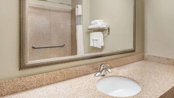 A bathroom with a granite countertop, a white sink, a mirror, and a towel rack with folded towels.