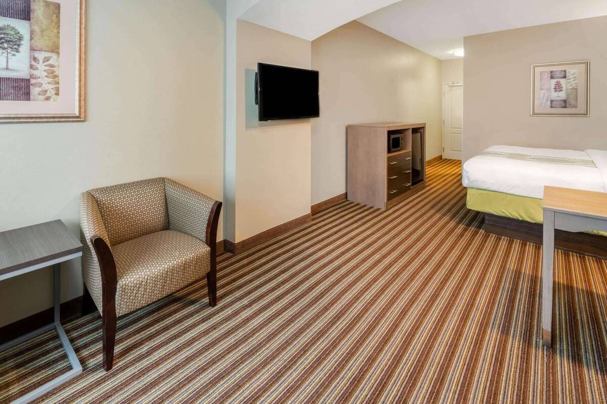 Une chambre d’hôtel équipée d’un lit, d’une chaise, d’un bureau, d’une télévision et d’un four à micro-ondes.