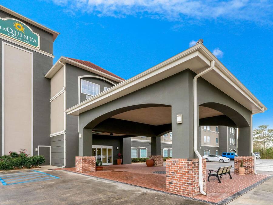 A La Quinta Inn & Suites with a covered entrance, brick pillars, and a parking lot.