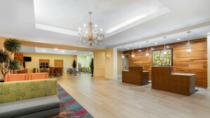 A spacious lobby with a reception desk, seating area, and a chandelier.