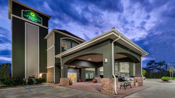 A hotel with a prominent sign, a covered entrance, and a parking area.