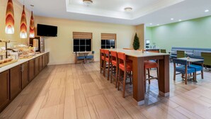 A modern dining area with a long counter, multiple chairs, and pendant lights.