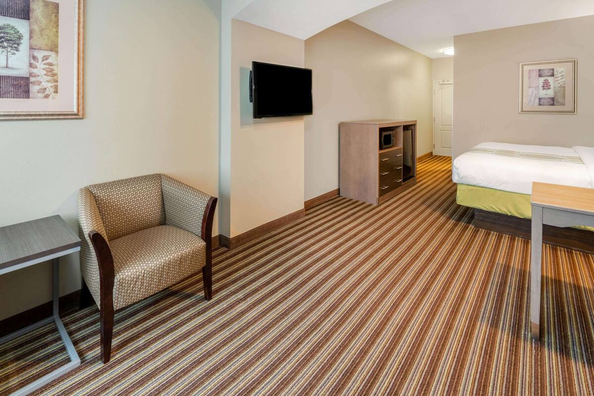 Une chambre d’hôtel comprenant un lit, un bureau, une chaise, une télévision et une armoire.