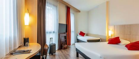 Una habitación de hotel con cama, escritorio, silla, televisor y maleta.