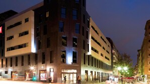 Un hotel moderno con un llamativo letrero de "ibis", varios pisos y una entrada a nivel de calle.